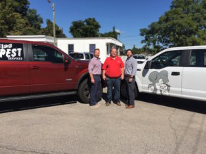 Flag pest and Northwest exterminating employees standing in front of company vans