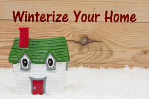 winterize your home text written on wooden background with a cartoon house sitting on snow