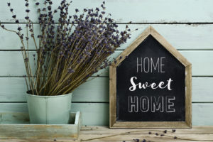 closeup of a house-shaped chalkboard with the text home sweet home and a plant beside it